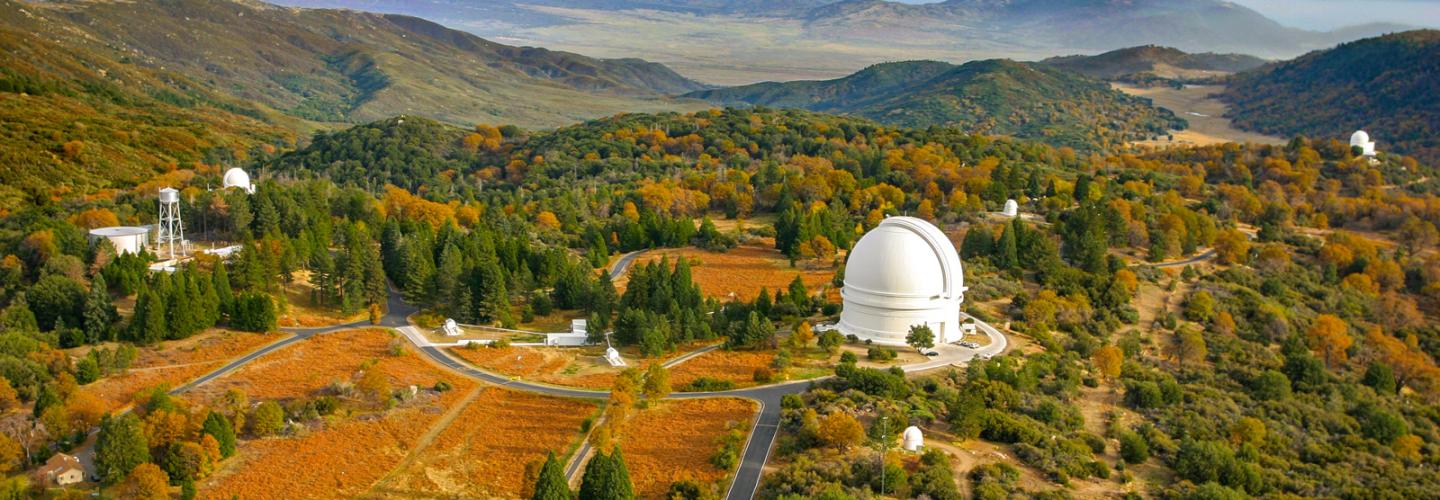 An image of the county side with a white telescope dome on the ground.