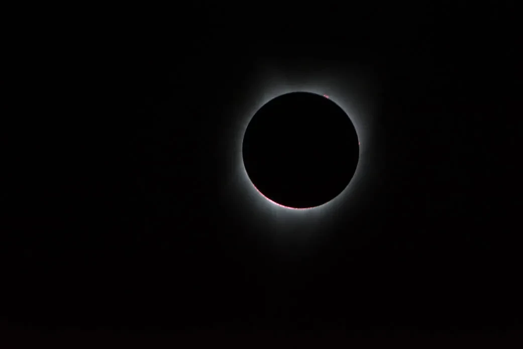 Image of the Sun with the Moon in front of it, with solar corona coming out from behind the circular Moon