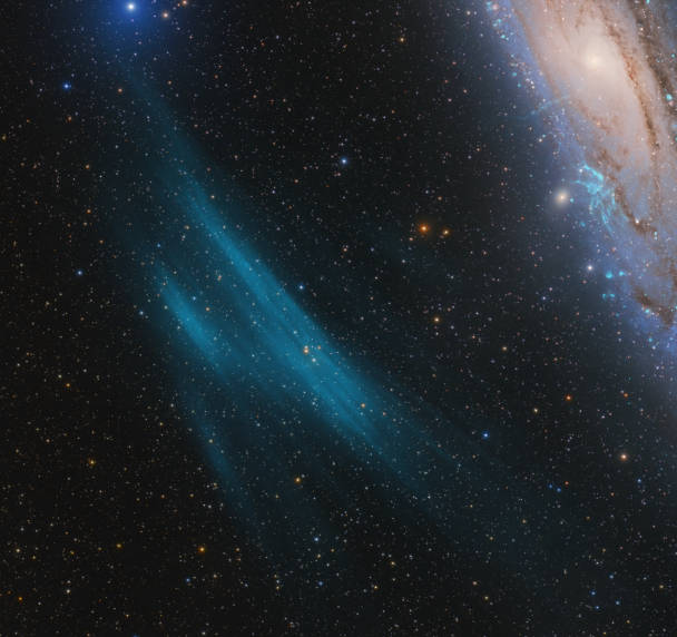 Close up of roughly curved cloud of blue gas in space, next to Andromeda spiral galaxy