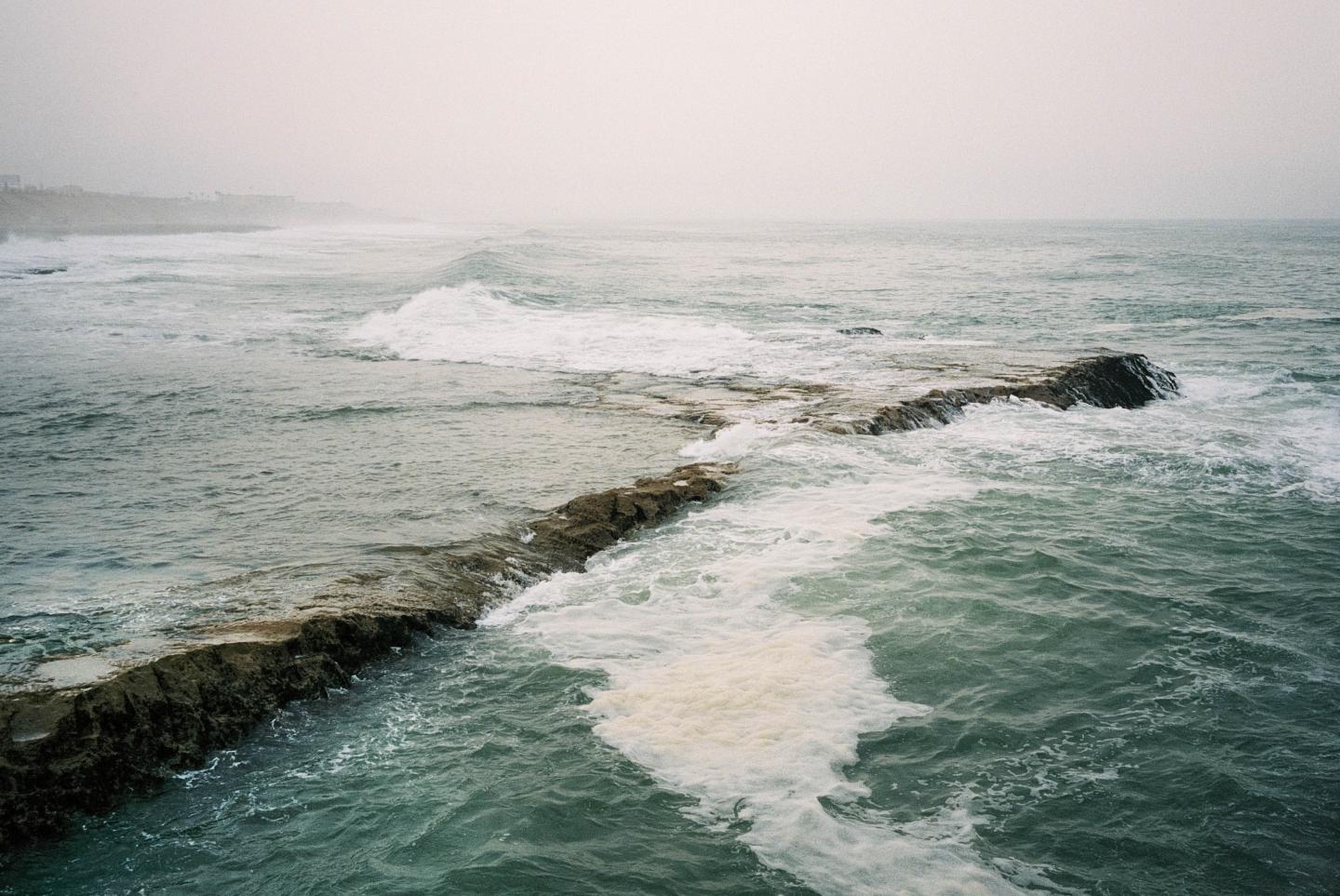 photo of the sea hitting the rocky shore