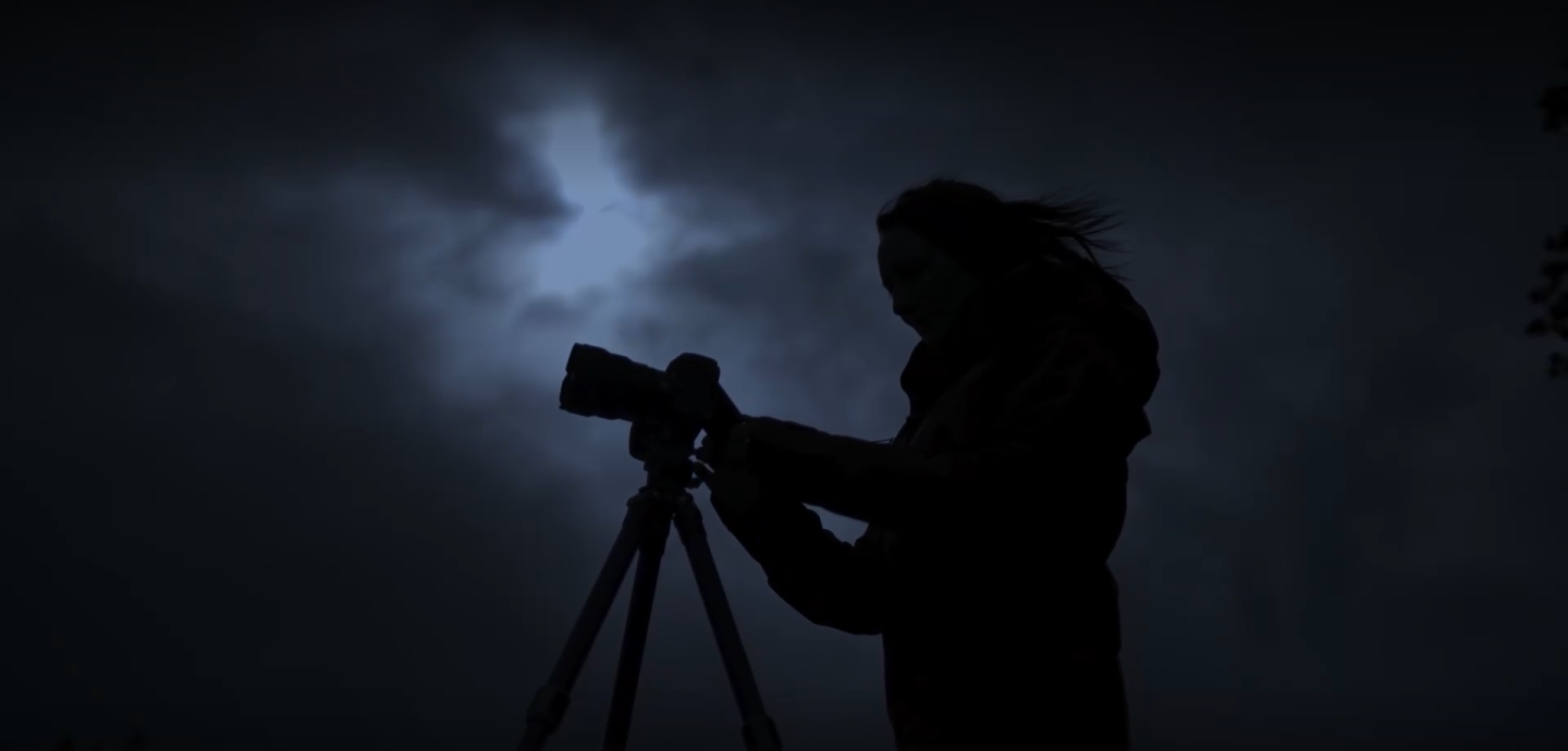 Silhouetted image of woman with camera against a dark sky