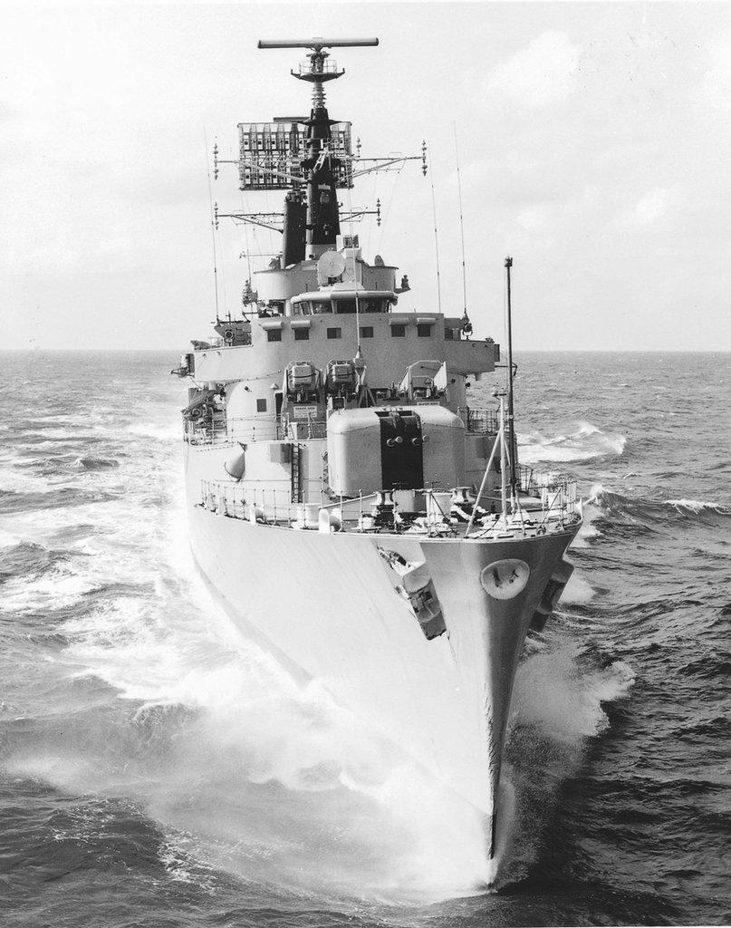 a b&w photo of a war ship ploughing through the sea