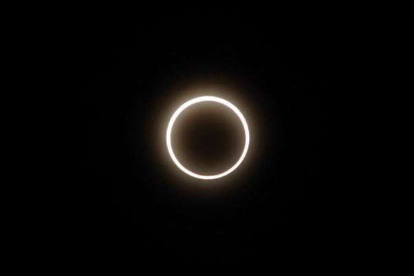 Image of an annular eclipse. A black background with a glowing orange ring around a black circle. 