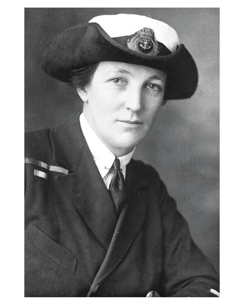 A b&w photo of a woman wearing a Wren's naval uniform which includes a hat 