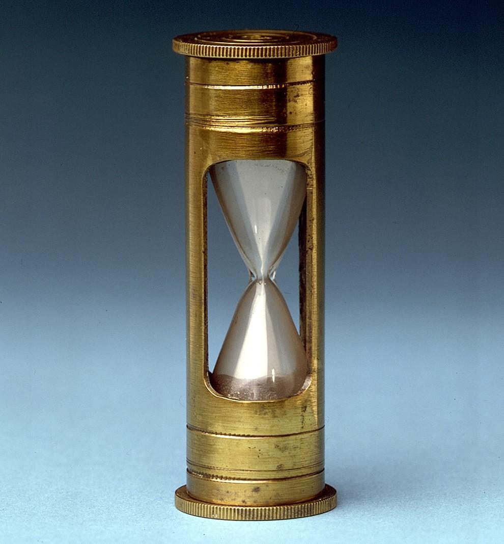 Image of a nautical log glass, which is a bronze cylindrical tube with a hourglass embedded in it