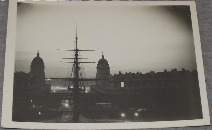 Old photo from the Queen's House roof of the Old Royal Naval College and a ship in the foreground, with the sky lit up with a bright white glow