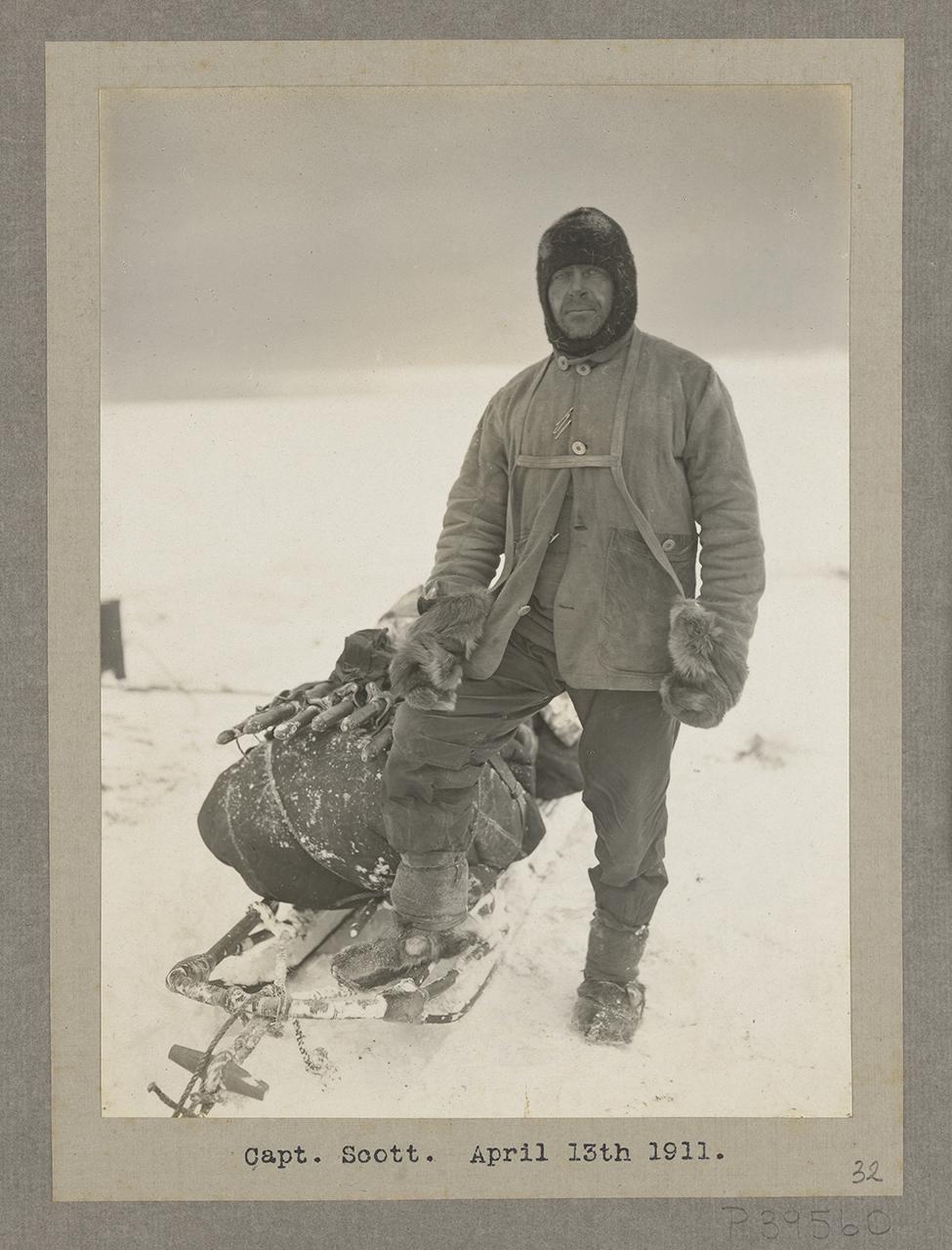 Image of Robert Falcon Scott in polar territory wearing heavy polar gear, leaning on a sled