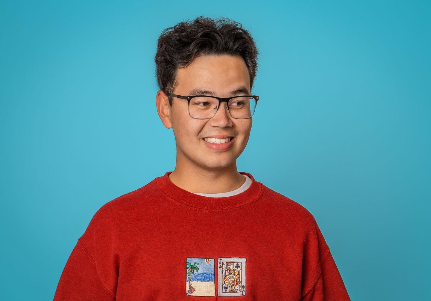 Image of James Trickey comedian, smiling at the camera wearing a red shirt