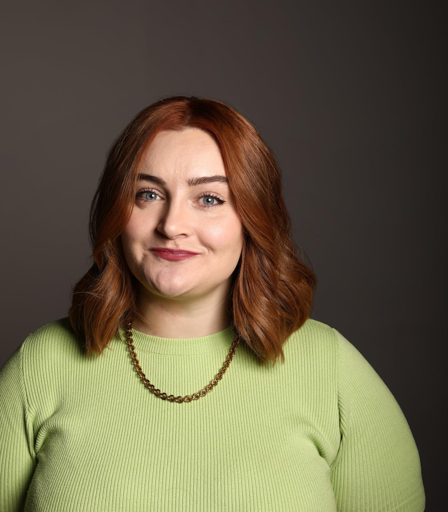 Image of comedian Kathryn Higgins, who has short brown hair and is wearing a lime green jumper