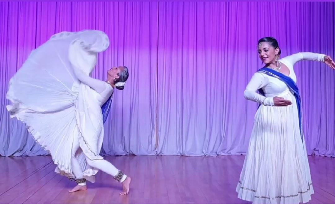purple curtain background with two ladies dancing Kathak 