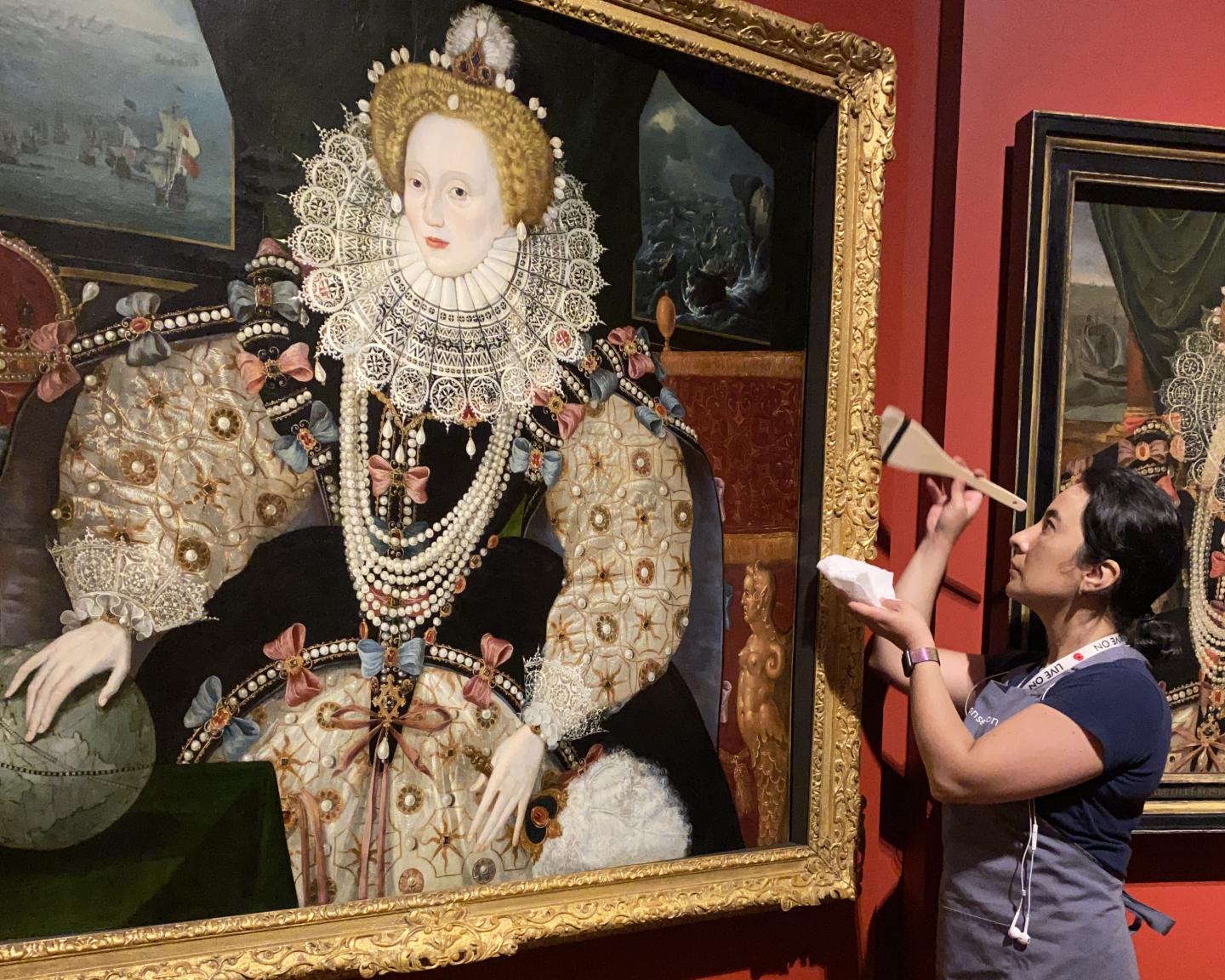 A museum conservator cleans the frame of a portrait of Elizabeth I