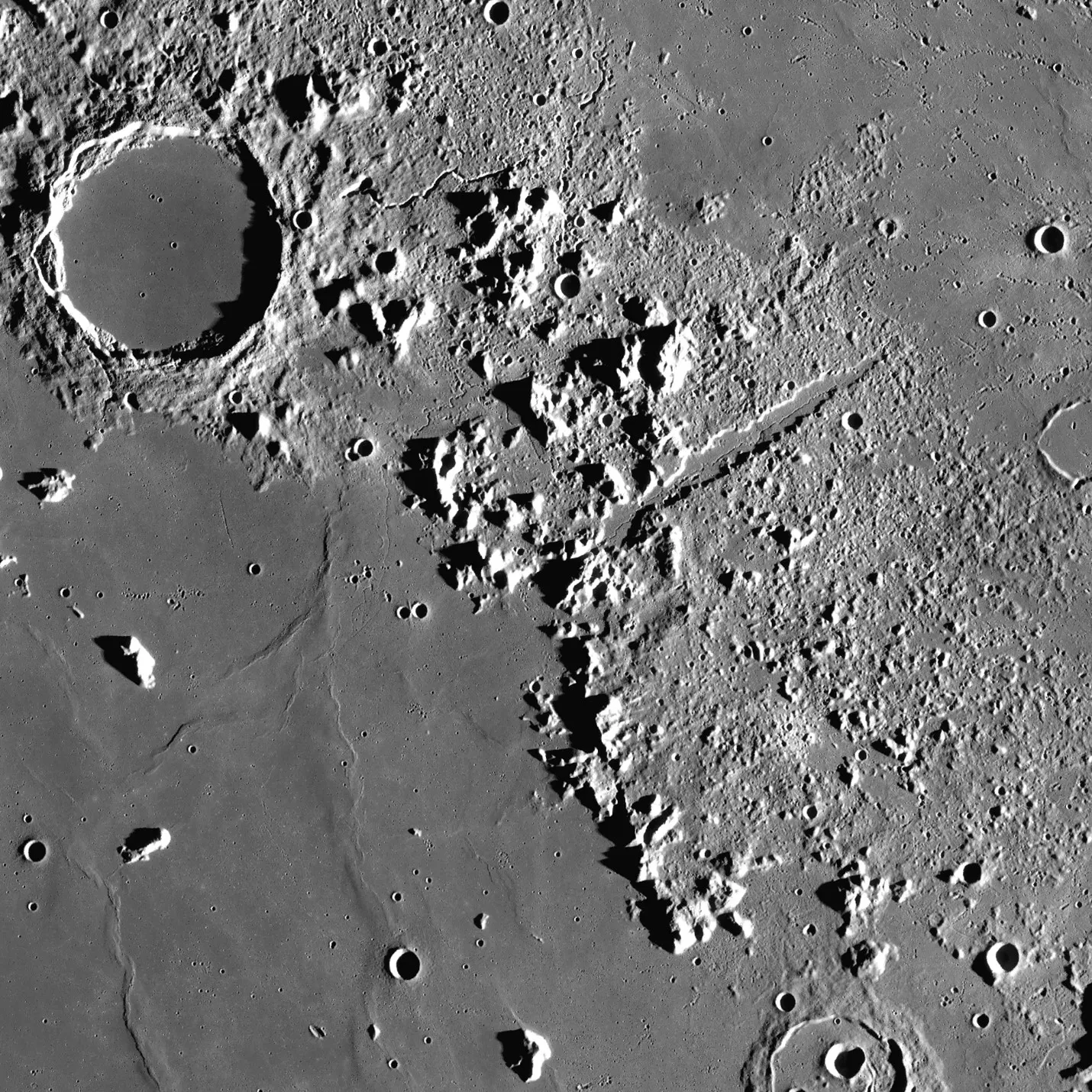 Photo of the lunar surface showing a circular crater and a mountain range