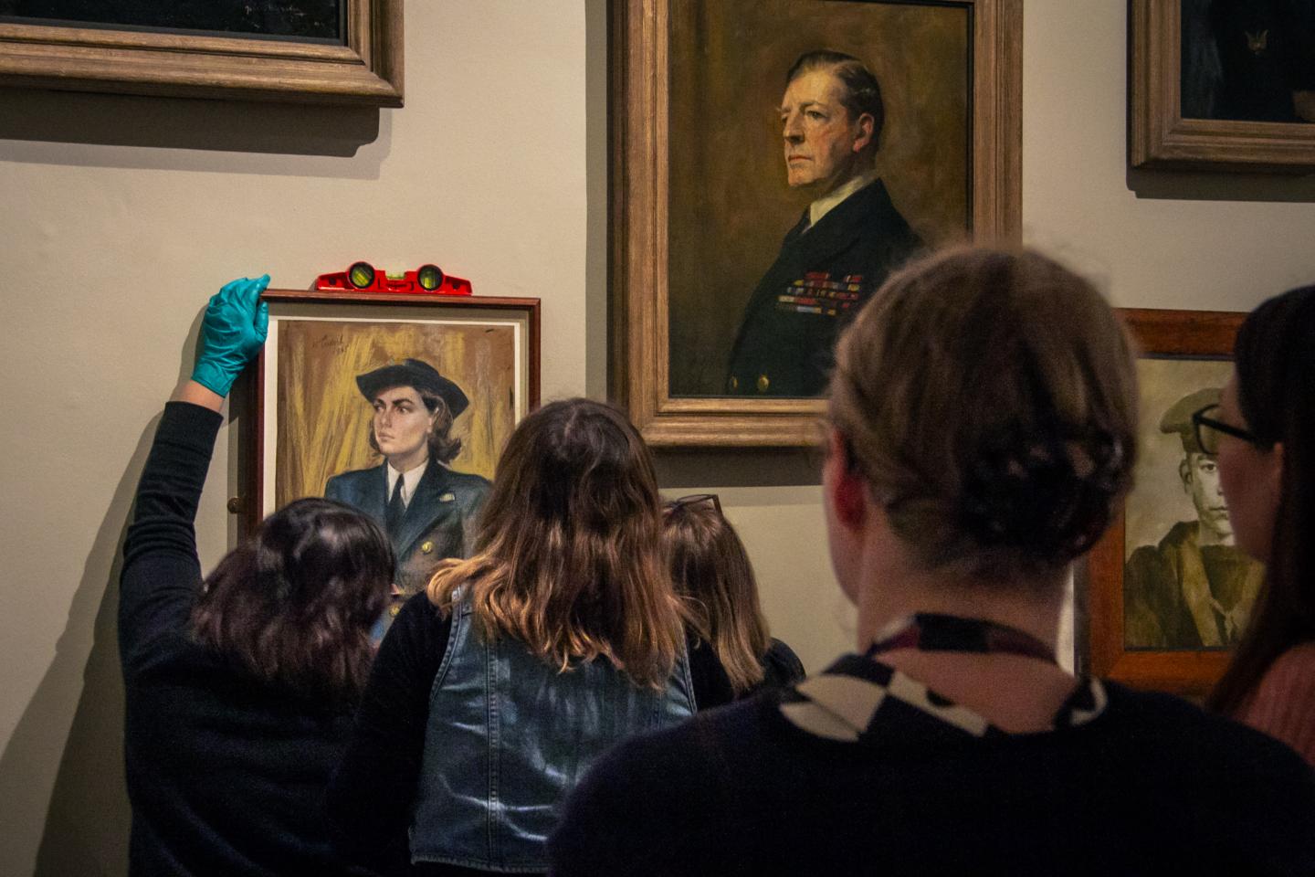 Art object handlers use a spirit level to try and make sure a painting is hanging straight at the Queen's House