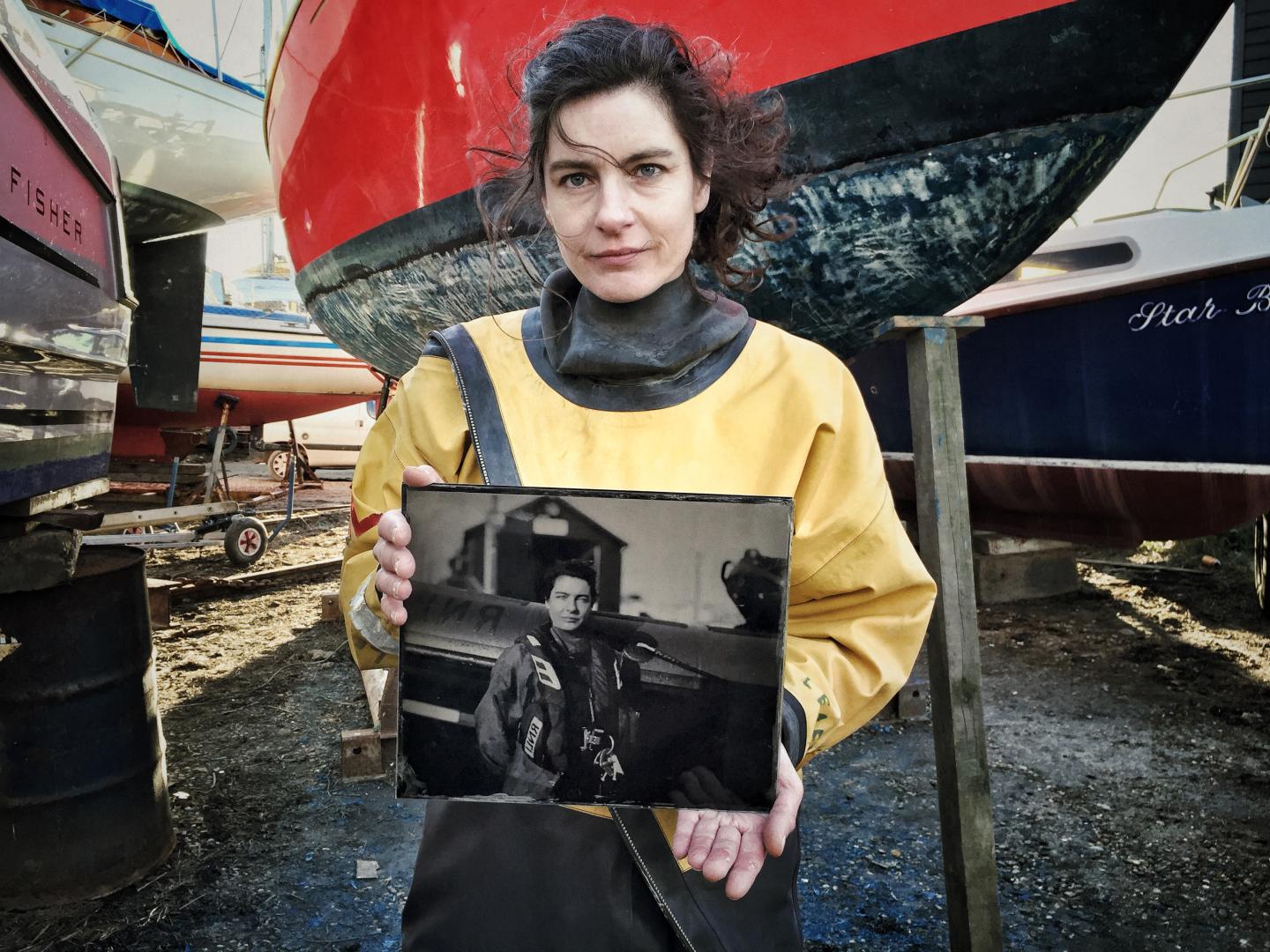 An RNLI lifeboat volunteer holds a glass plate photograph of herself