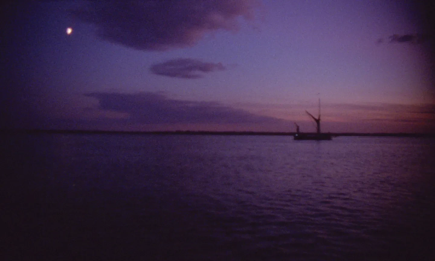 A purple sky and water landscape with a Thames barge in the distance, moored for the evening.