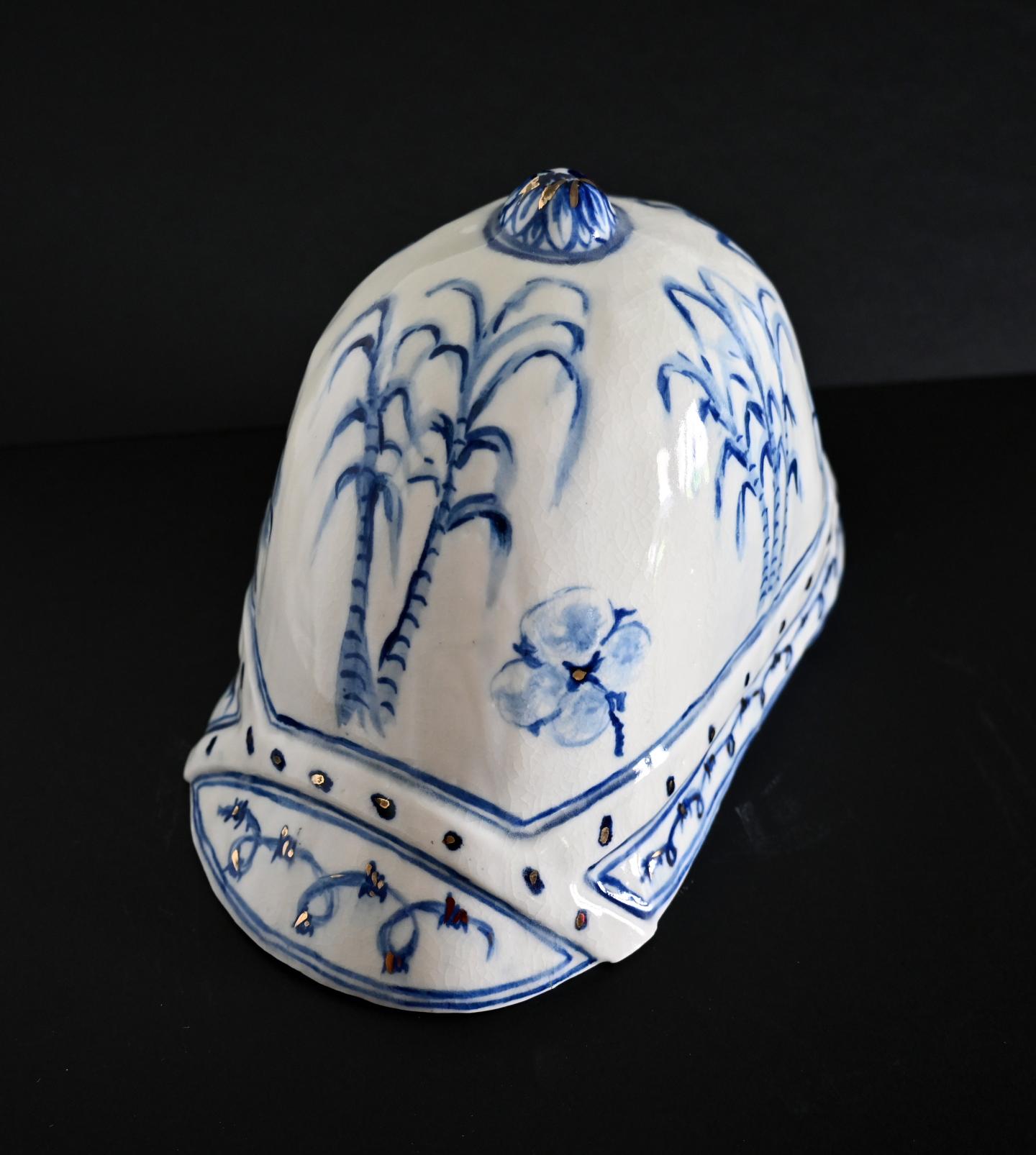 A pith helmet made from porcelain, with blue and gold underglaze decoration