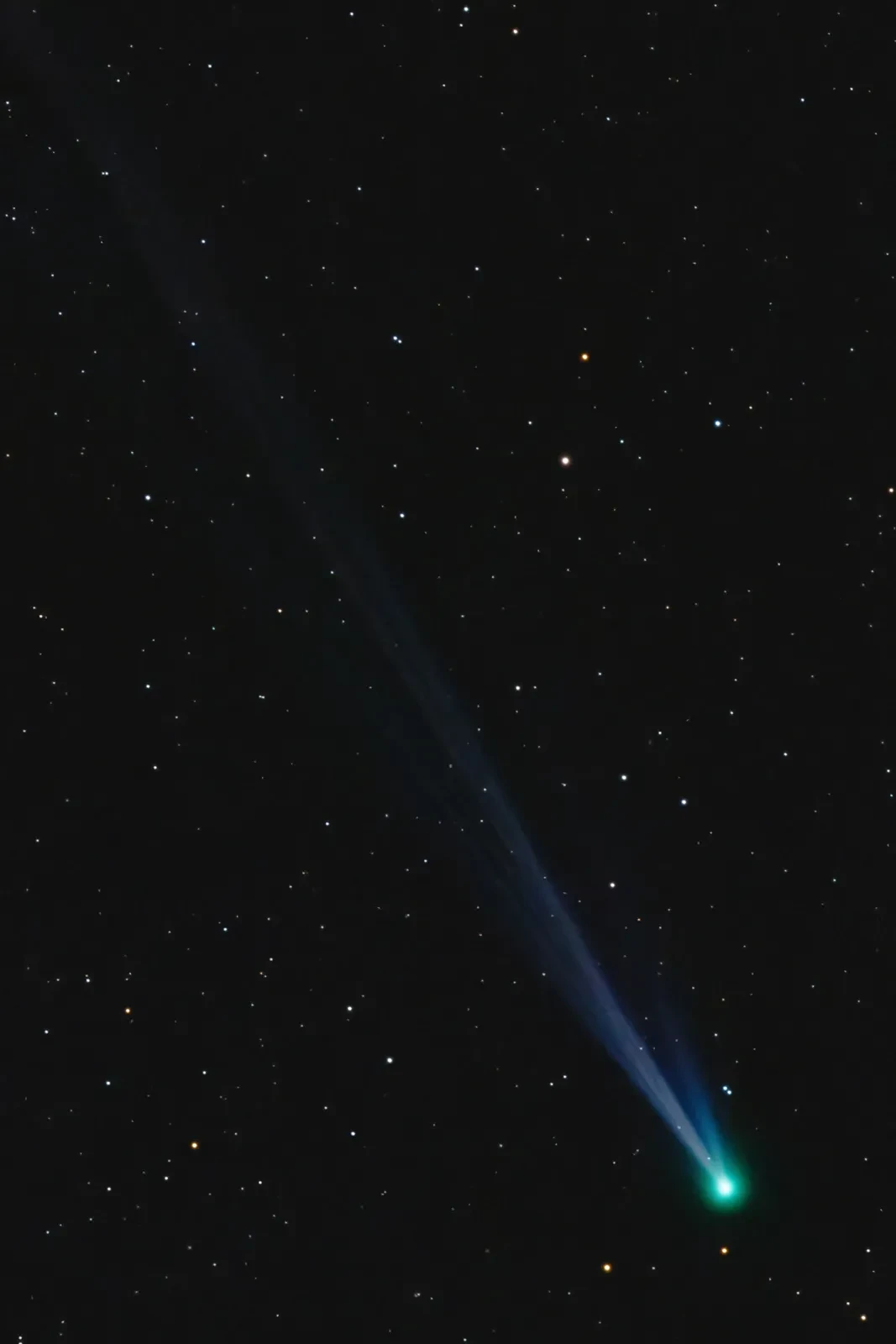 Telescope view of a comet - the comet itself is visible in the bottom right corner, with its tail streaming diagonally across the camera view