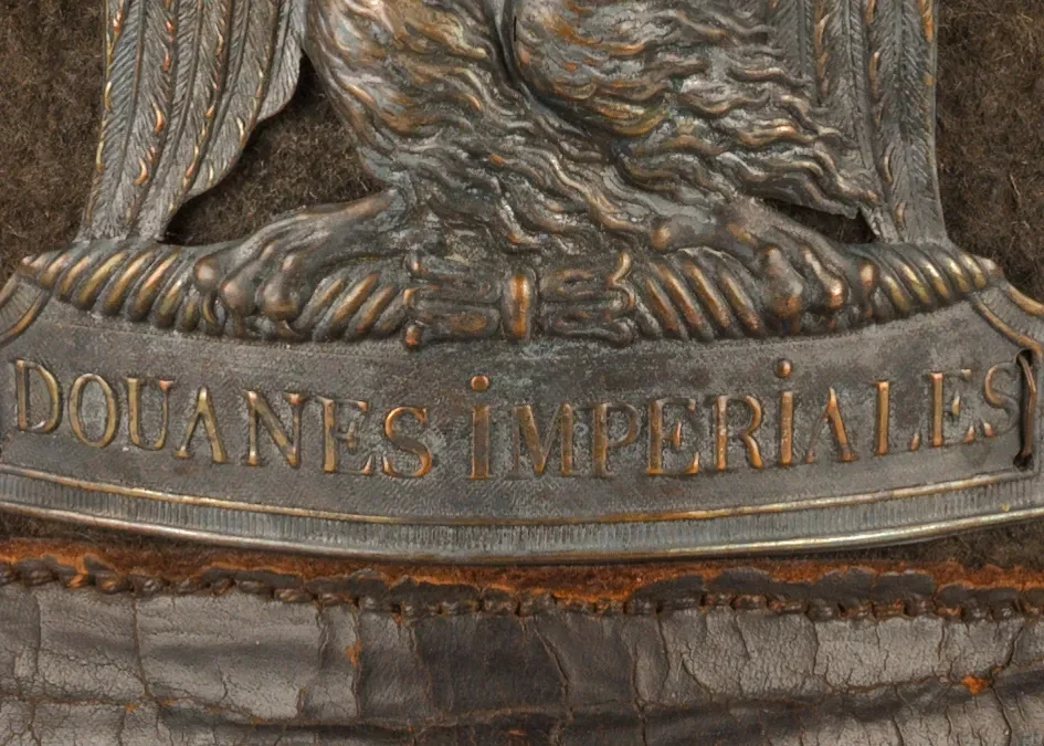Detail of a French Napoleonic era uniform, showing a metal badge with the words 'Douanes Imperiales' visible