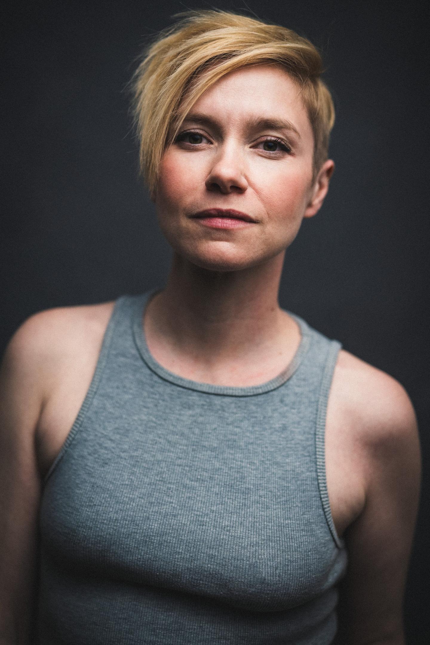 Sally Hodgkiss, wearing a grey vest, short blonde hair, looking at the camera