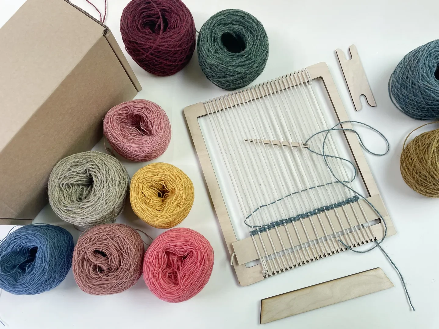 A box wool loom about to be worked on, with neat rolls of wool lying on the table next to it