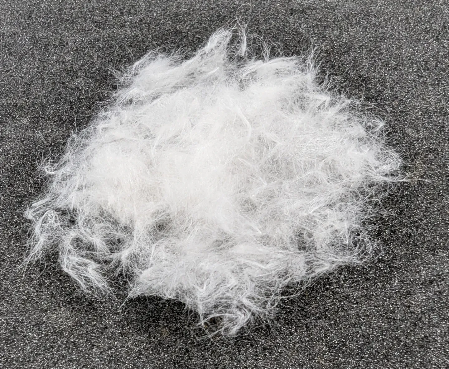 A pile of white, fluffy strands of paper laid out on a grey tabletop