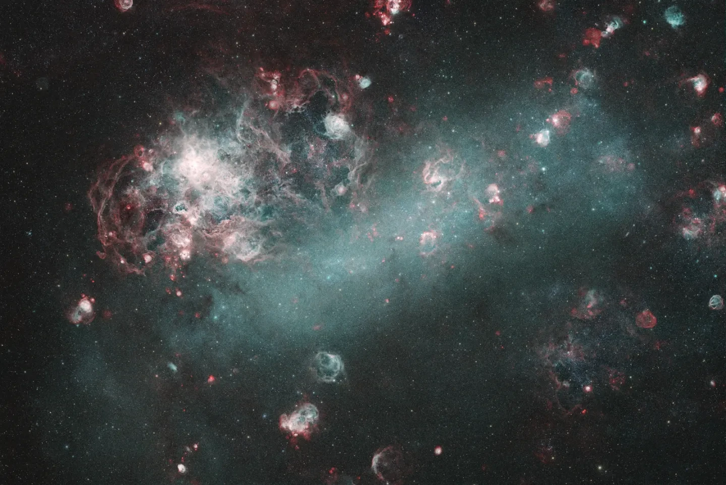 A dwarf galaxy and surrounding nebulae look like puffs of smoke in a dark sky.