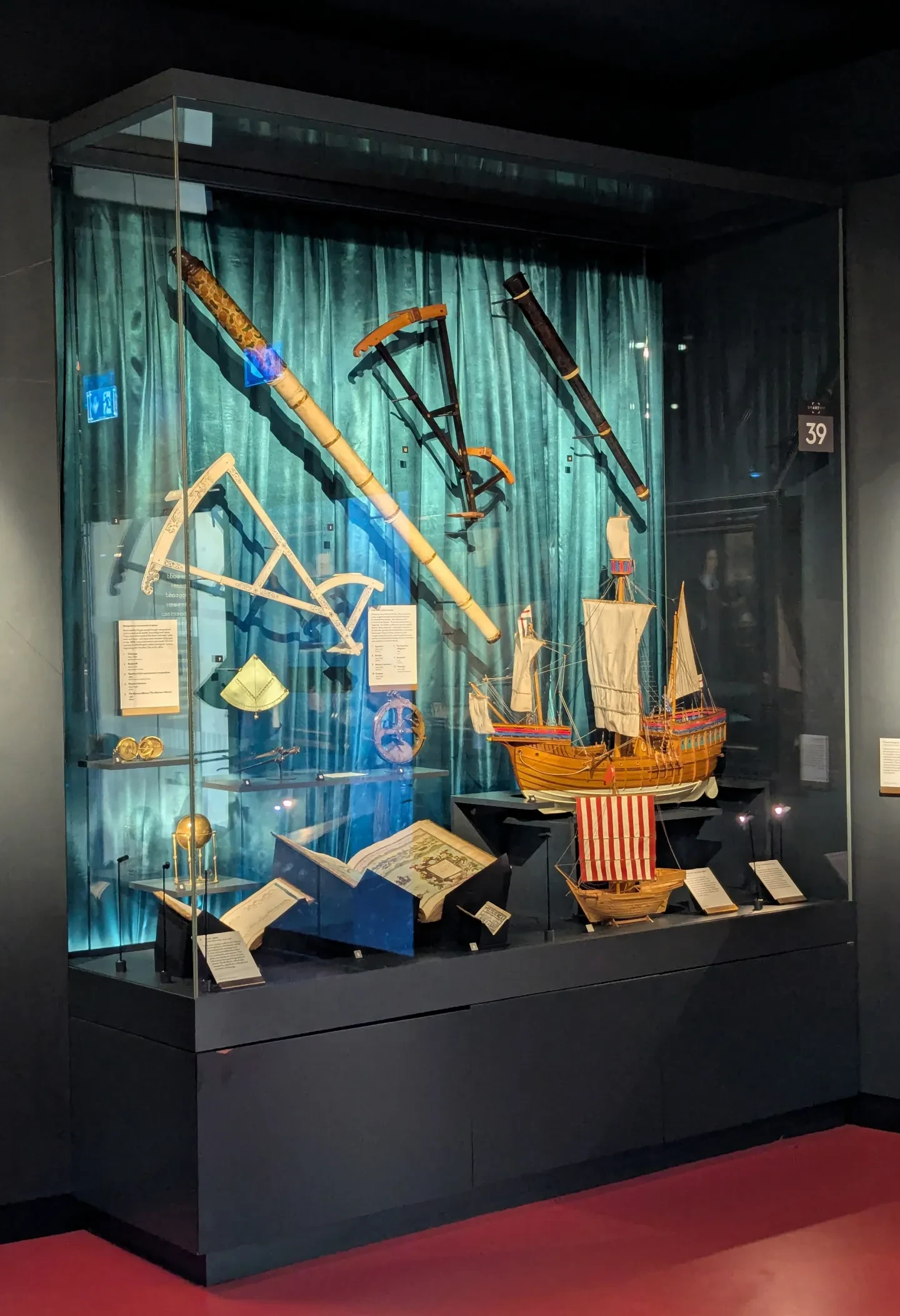 A Museum display cabinet filled with telescopes, books and navigational instruments