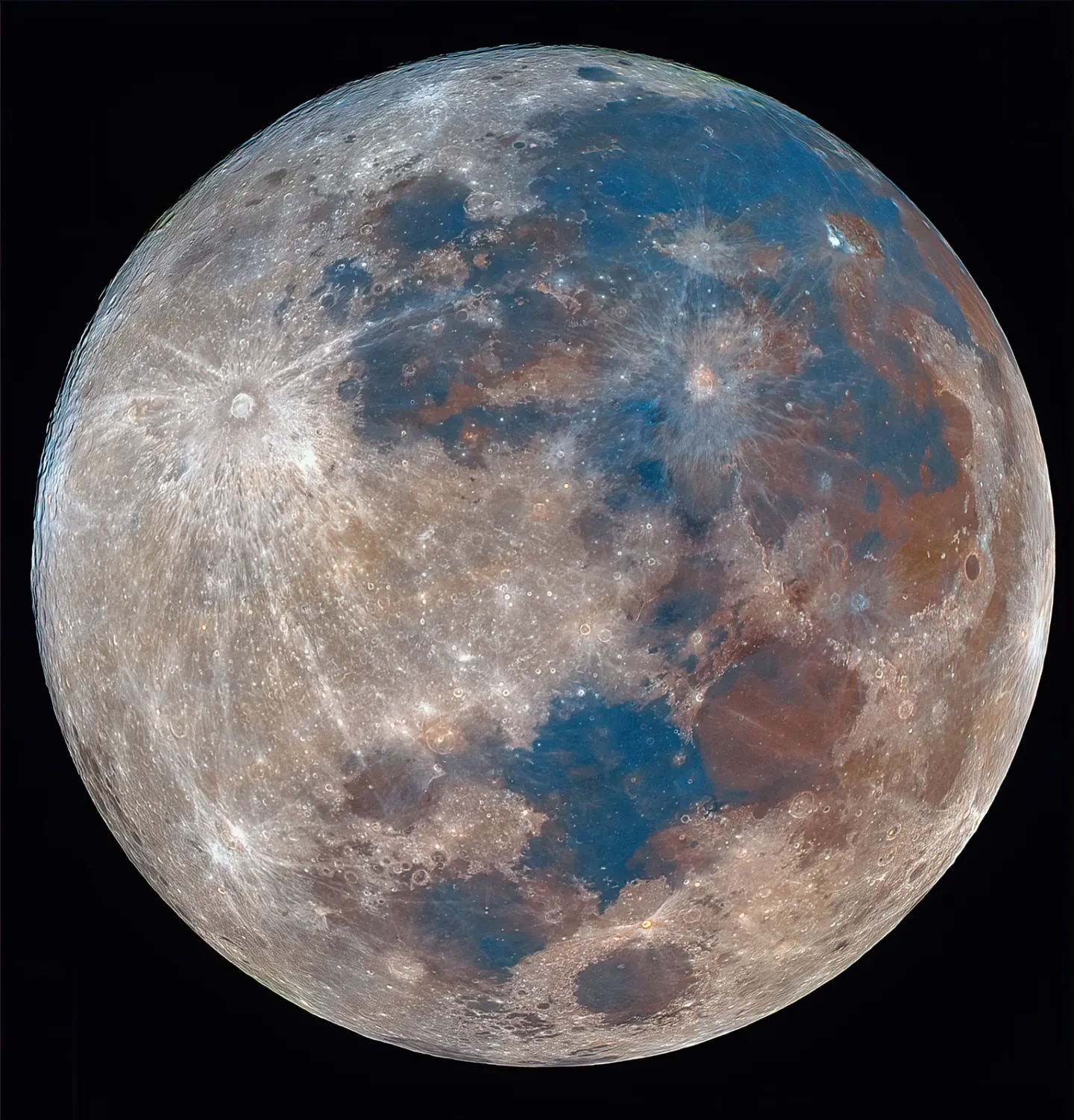 Photo of complete Moon in lots of detail with many areas highlighted in blues and rust colour with craters in bright white
