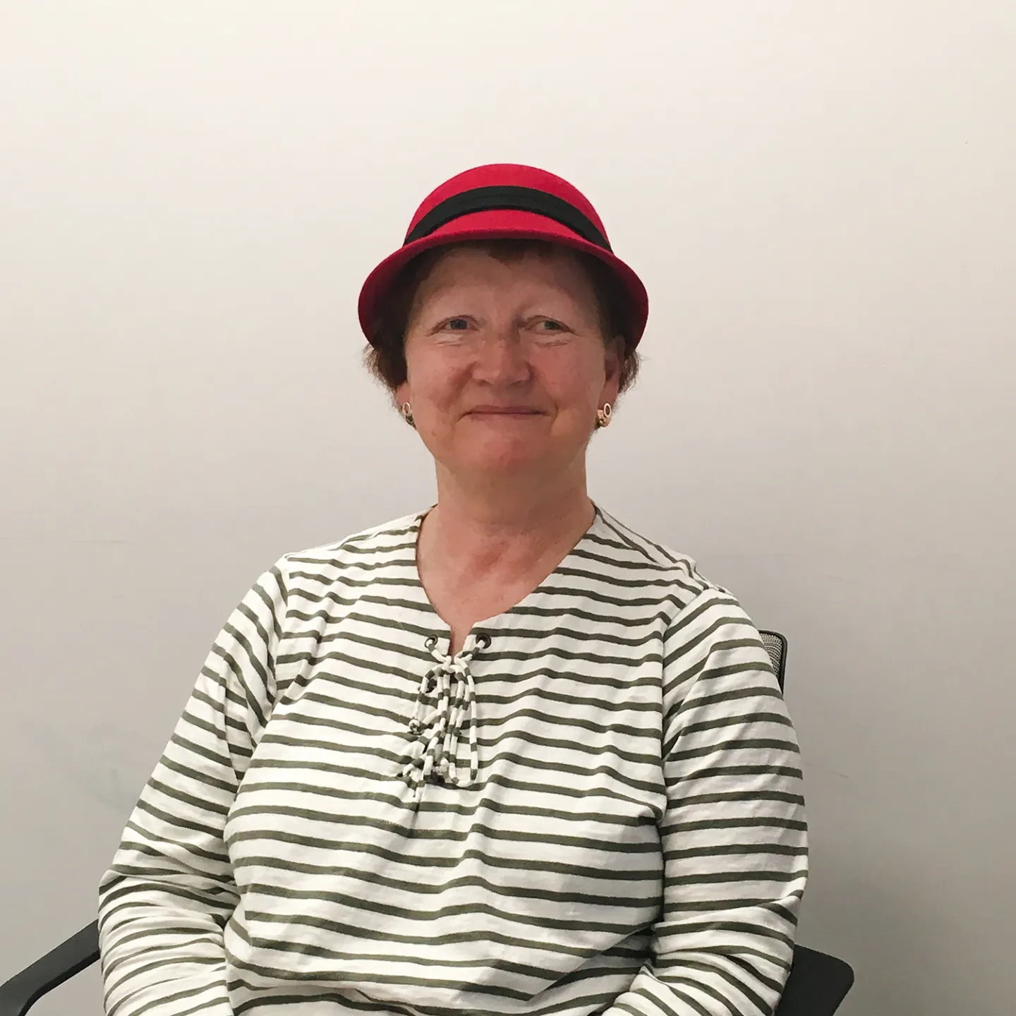 A woman wearing a red hat and striped top sits comfortably in a chair