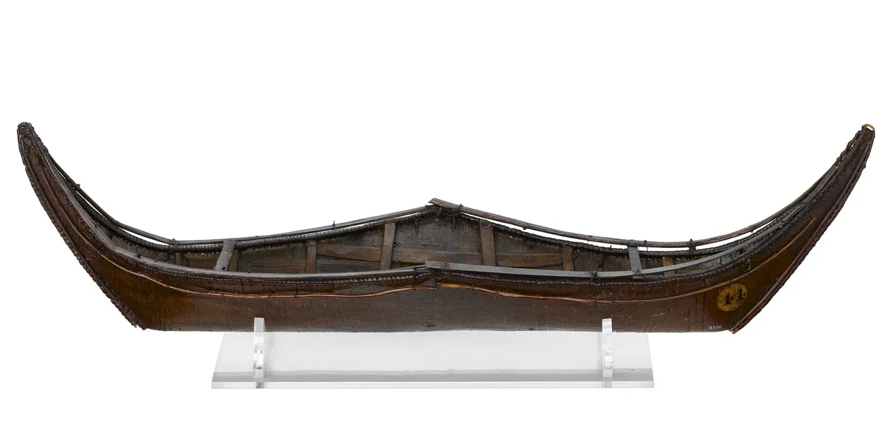 A wooden model of a canoe on a clear plastic mount