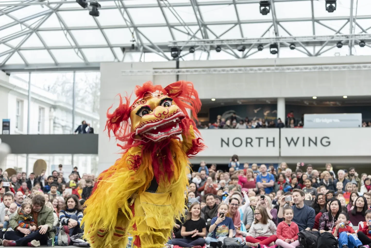 The image shows a person in a Chinese lion costume dancing in front of a crowd.