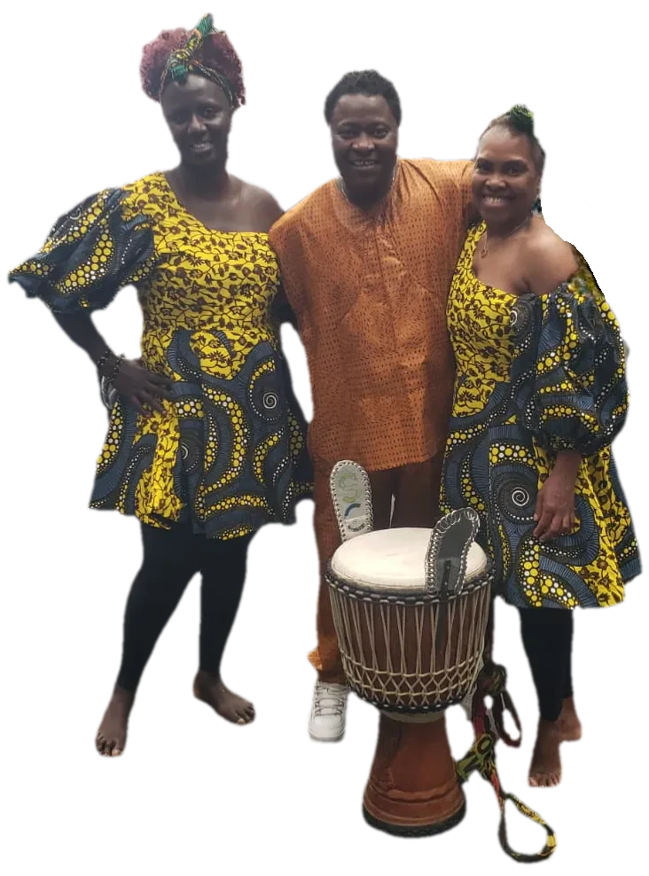 colour photo full body image of 2 black female dancers in bright African dress and a man in gold coloured trousers and shirt with a drum in the forefront of the photo