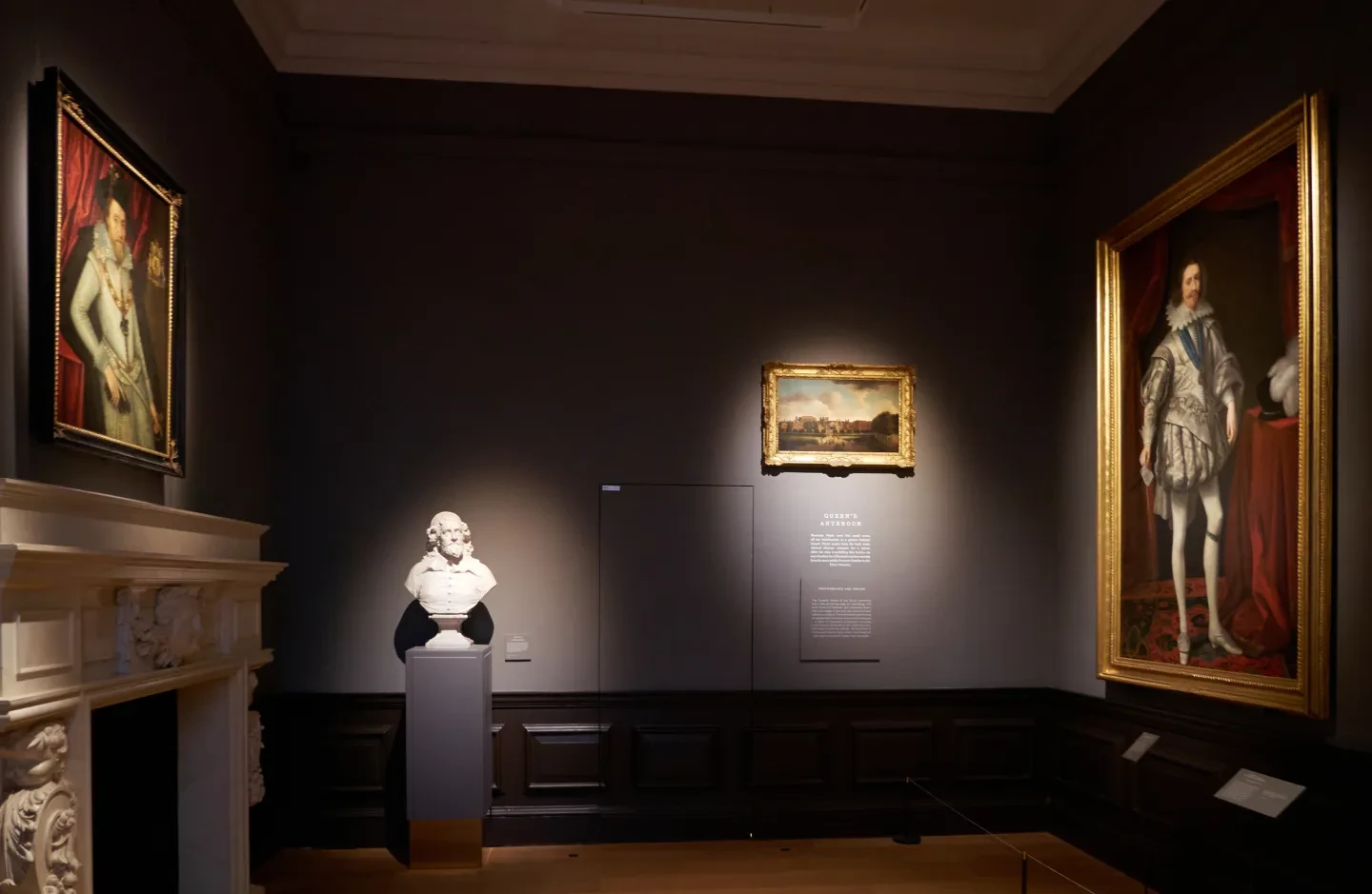 A grey room in an art gallery with paintings of James I and George Villiers hanging opposite each other