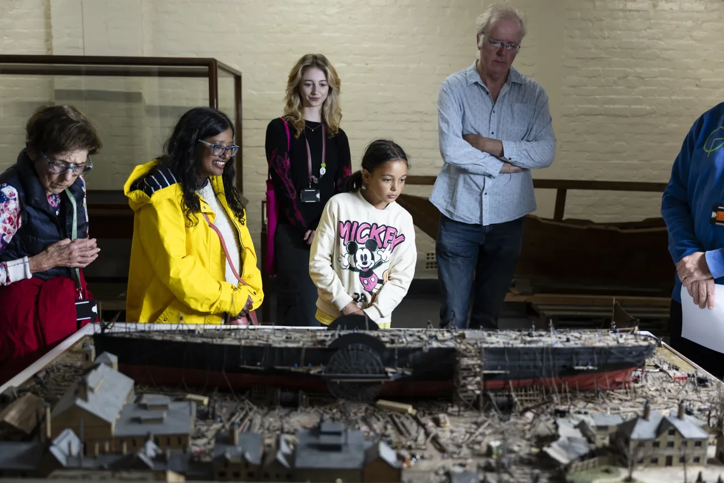 A group of people looking at a ship model 