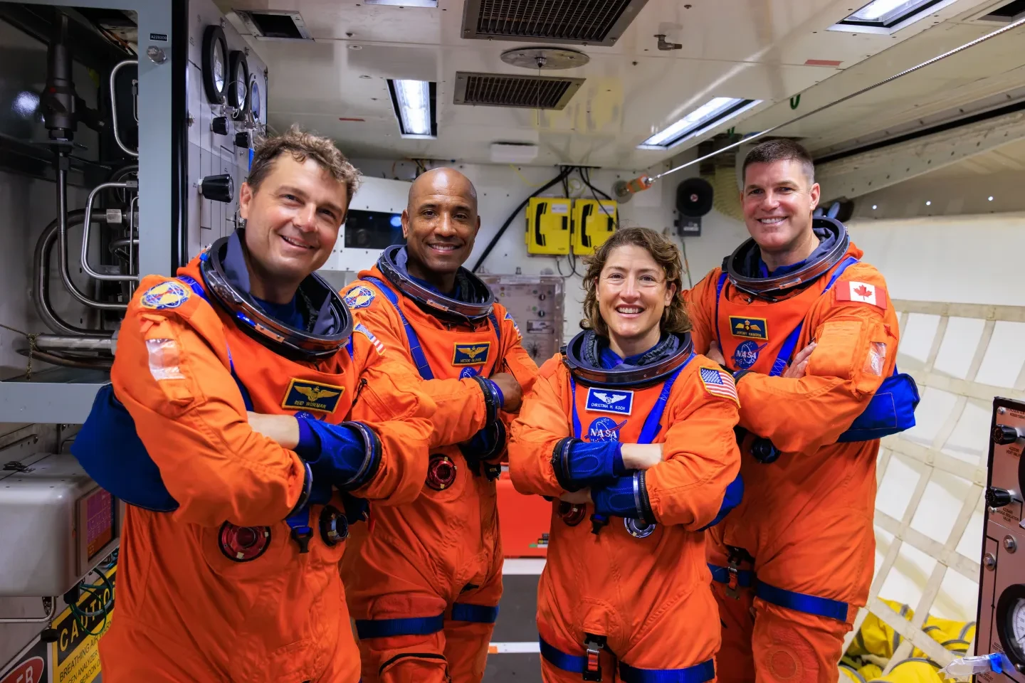 Four people, Artemis 2 crew in bright orange spacesuits 