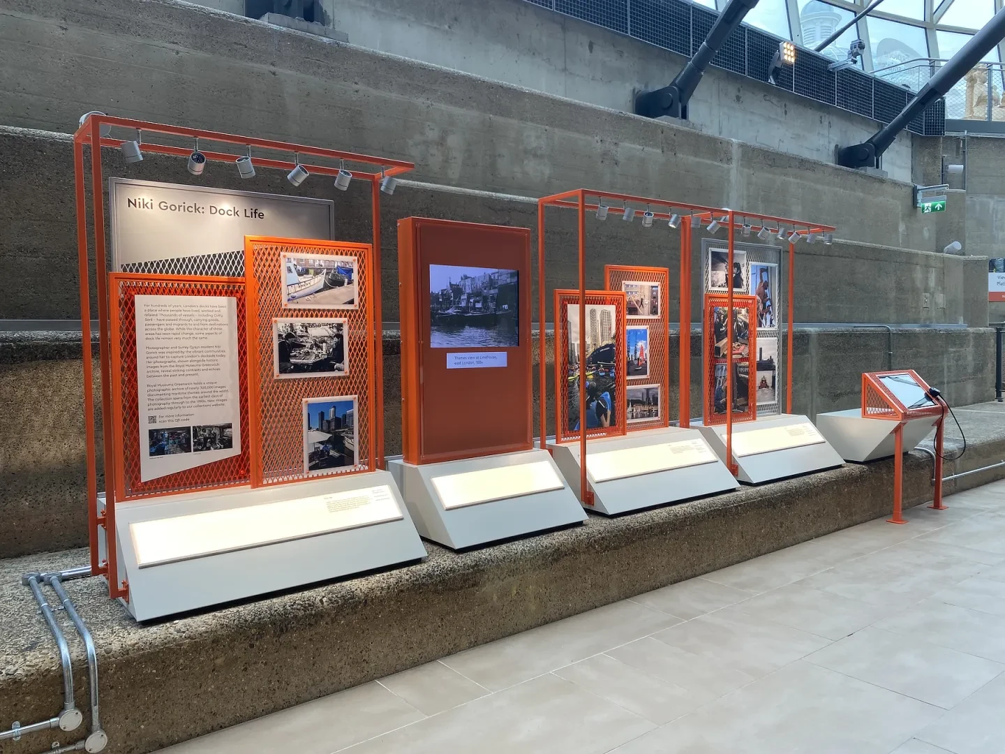 An orange gallery display featuring pictures of people working and living on London's docks