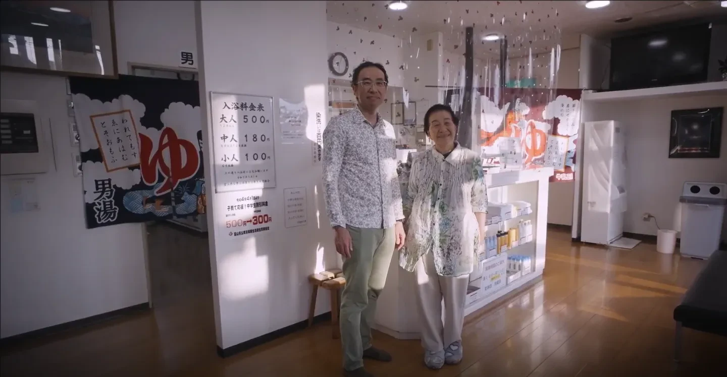 Photo of Takanobu Kurosaki and his mother standing in the entry of a traditional Japanese bathhouse