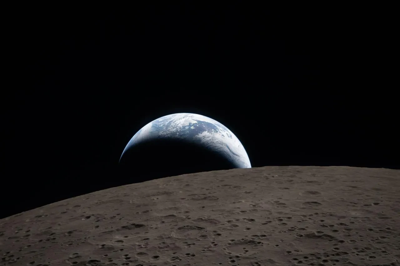 The Moon's limb in the foreground with a half crescent of Earth poking above, half in daylight