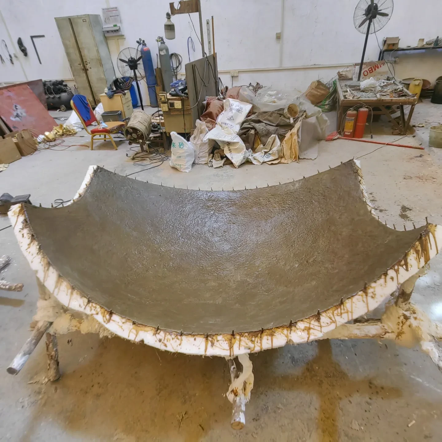 A brown segment of the Mirror Moon artwork propped up on metal bars as the wax dries