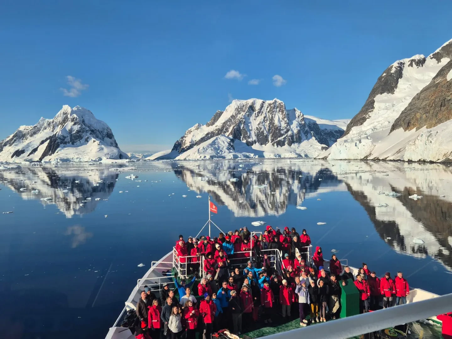 A group of passengers stand on the deck of an expedition ship