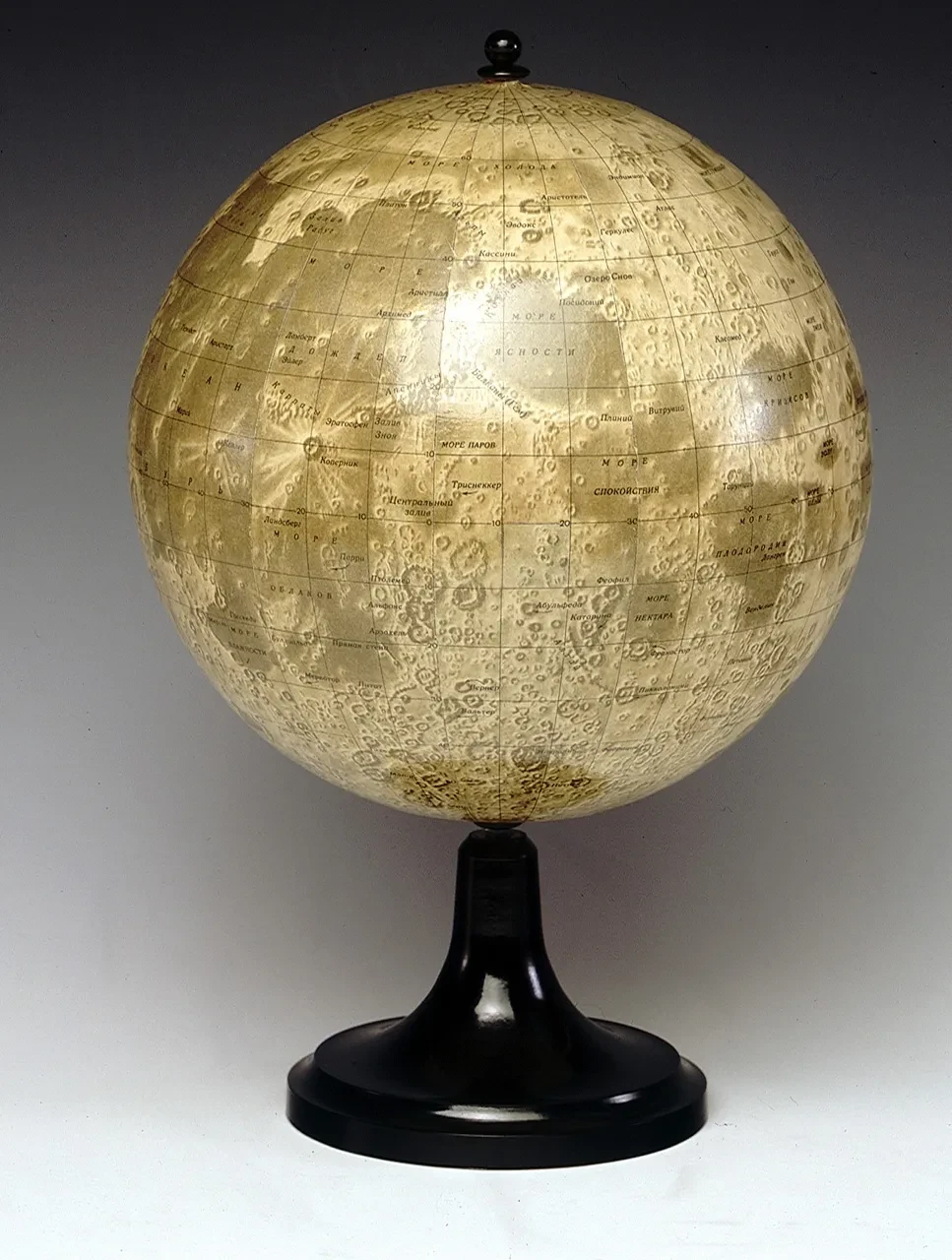 A yellowish green globe showing a map of the Moon, on a black circular stand