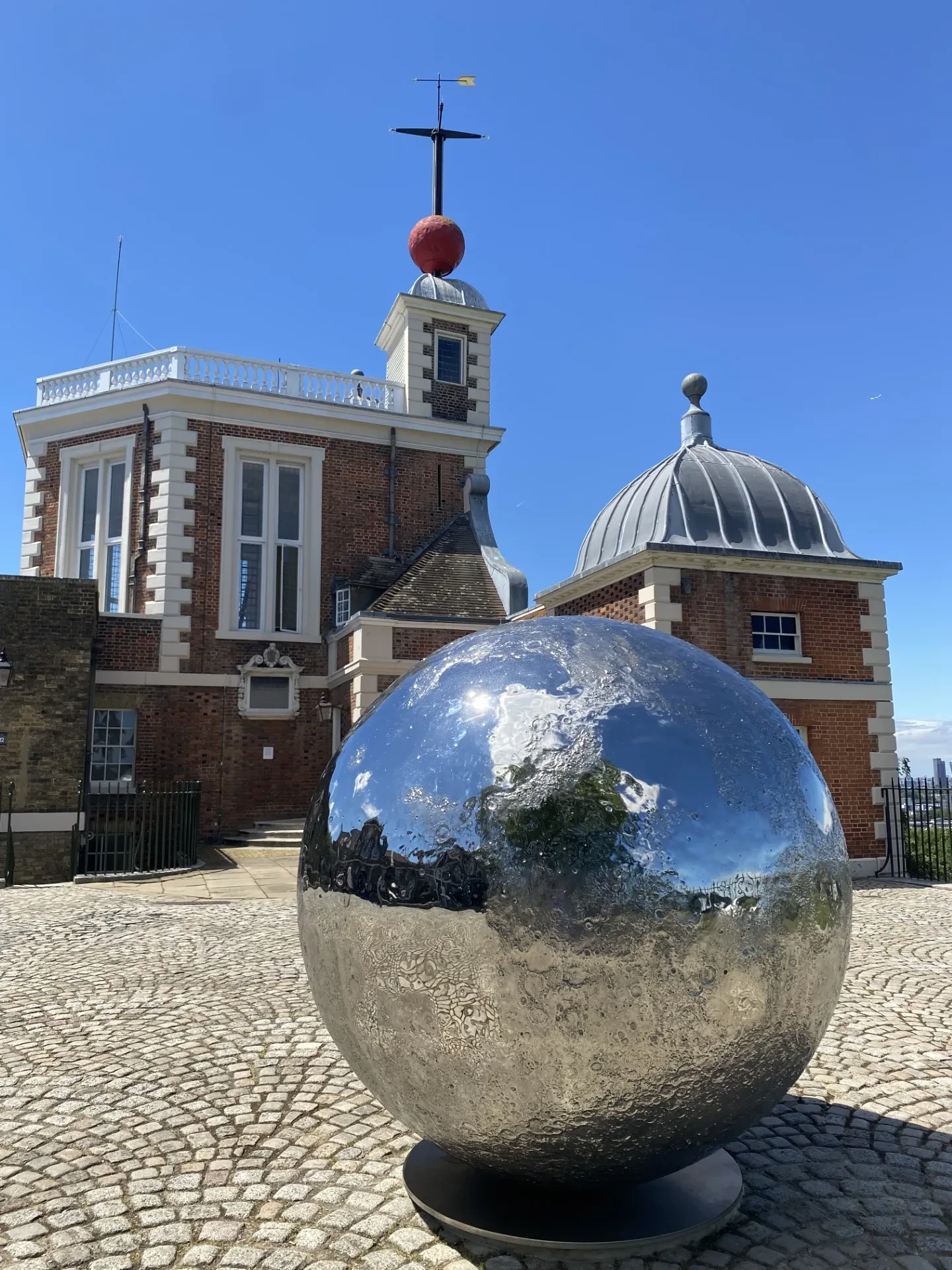 A shining metallic Moon sculpture sits in the courtyard in front of the Royal Observatory in Greenwich