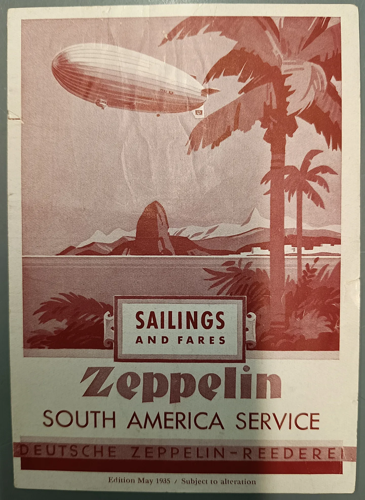 A photo of the front cover of a brochure for the Zeppelin South America Service. It depicts palm trees with a zeppelin in the distance.