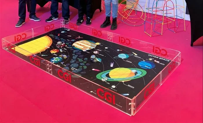 An activity on the floor made up of a floor sheet with planets on it surrounded by plexiglass