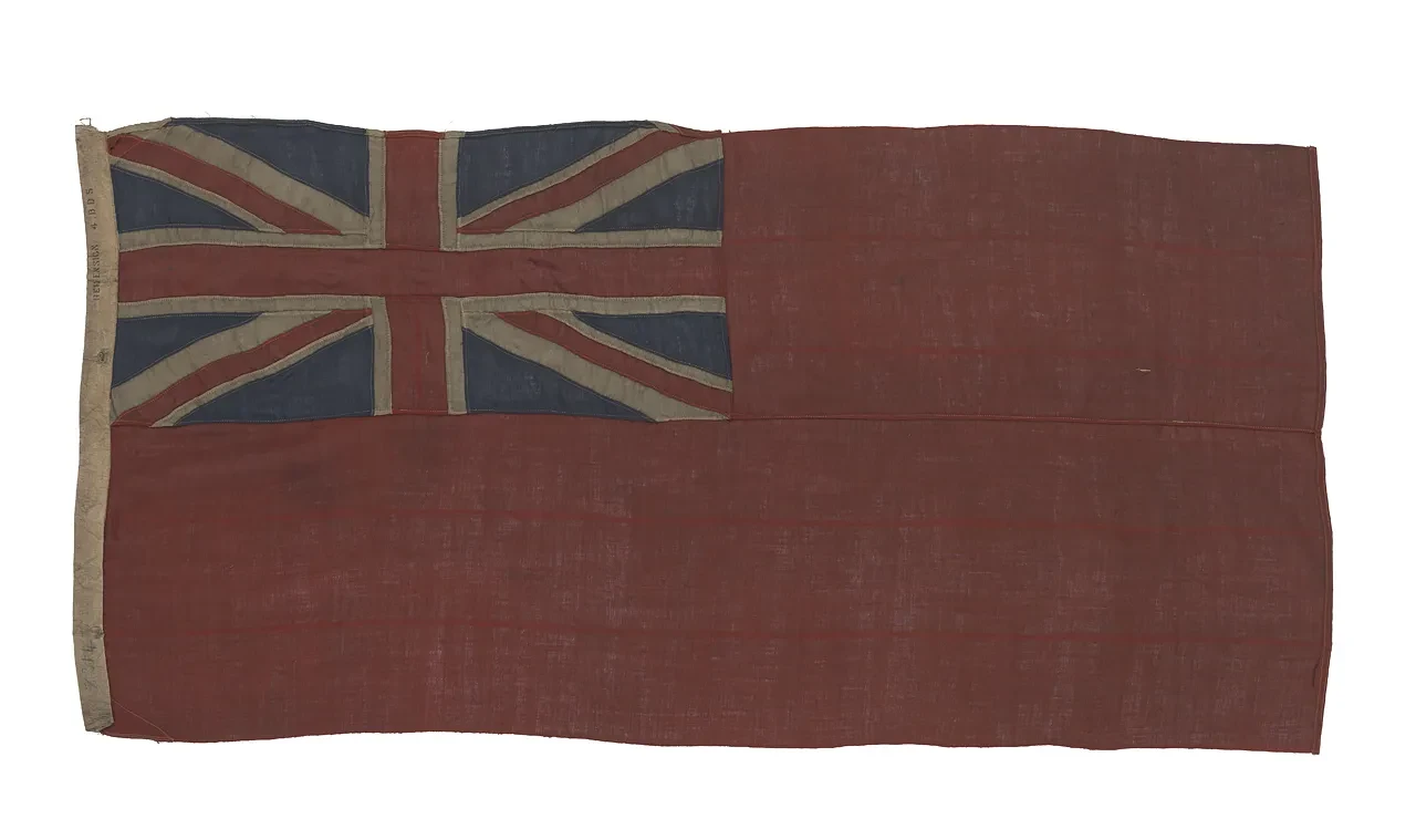 A British merchant ensign featuring a red backdrop with the Union flag in the top left corner