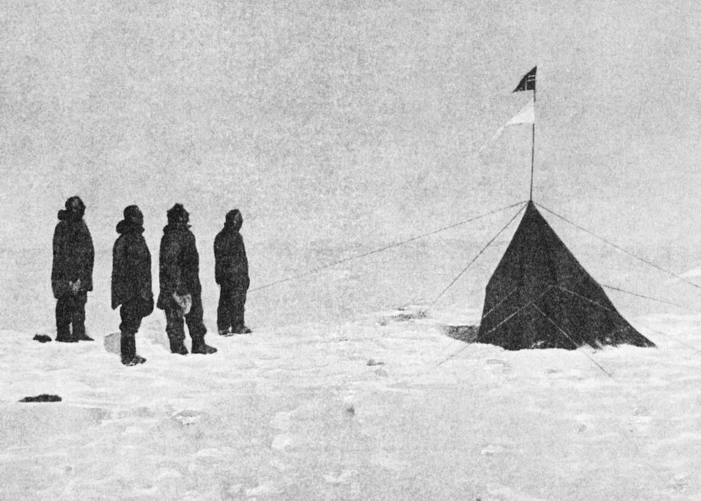 photograph showing the silhouette of four men in furs next to a small tent in an arctic setting.