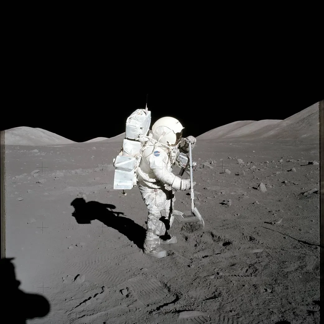 Harrison H. Schmitt in a space suit collecting lunar rake samples.