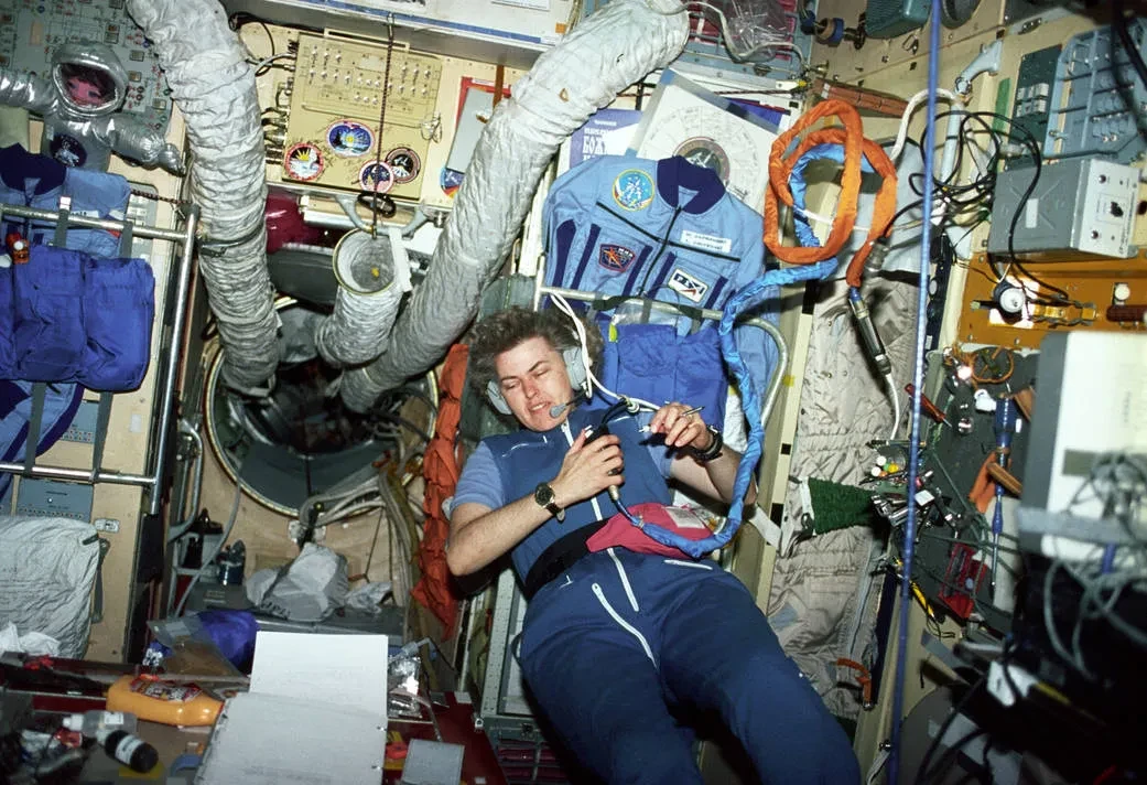 Astronaut Shannon Lucid surrounded by tech in a space station.