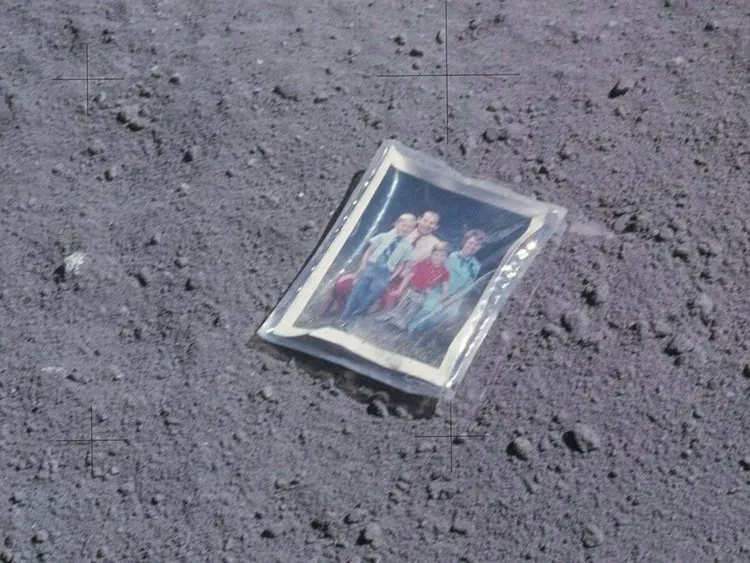 A plastic-wrapped photo of a family of four, on the surface of the moon.