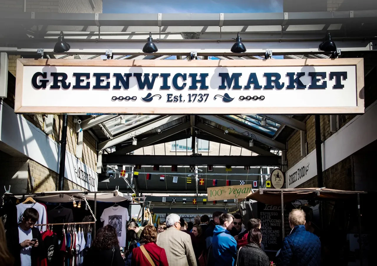A busy market scene under the sign 'Greenwich Market'.